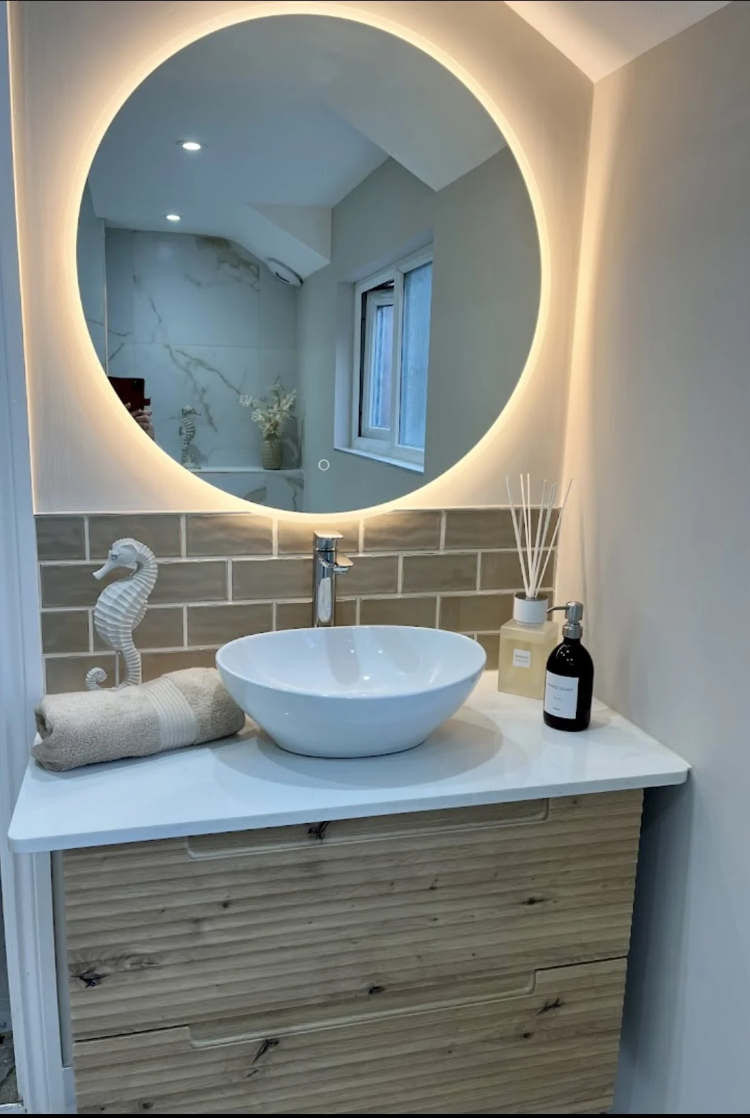 Oak vanity with vessel basin and illuminated round mirror — completed DDI bathroom