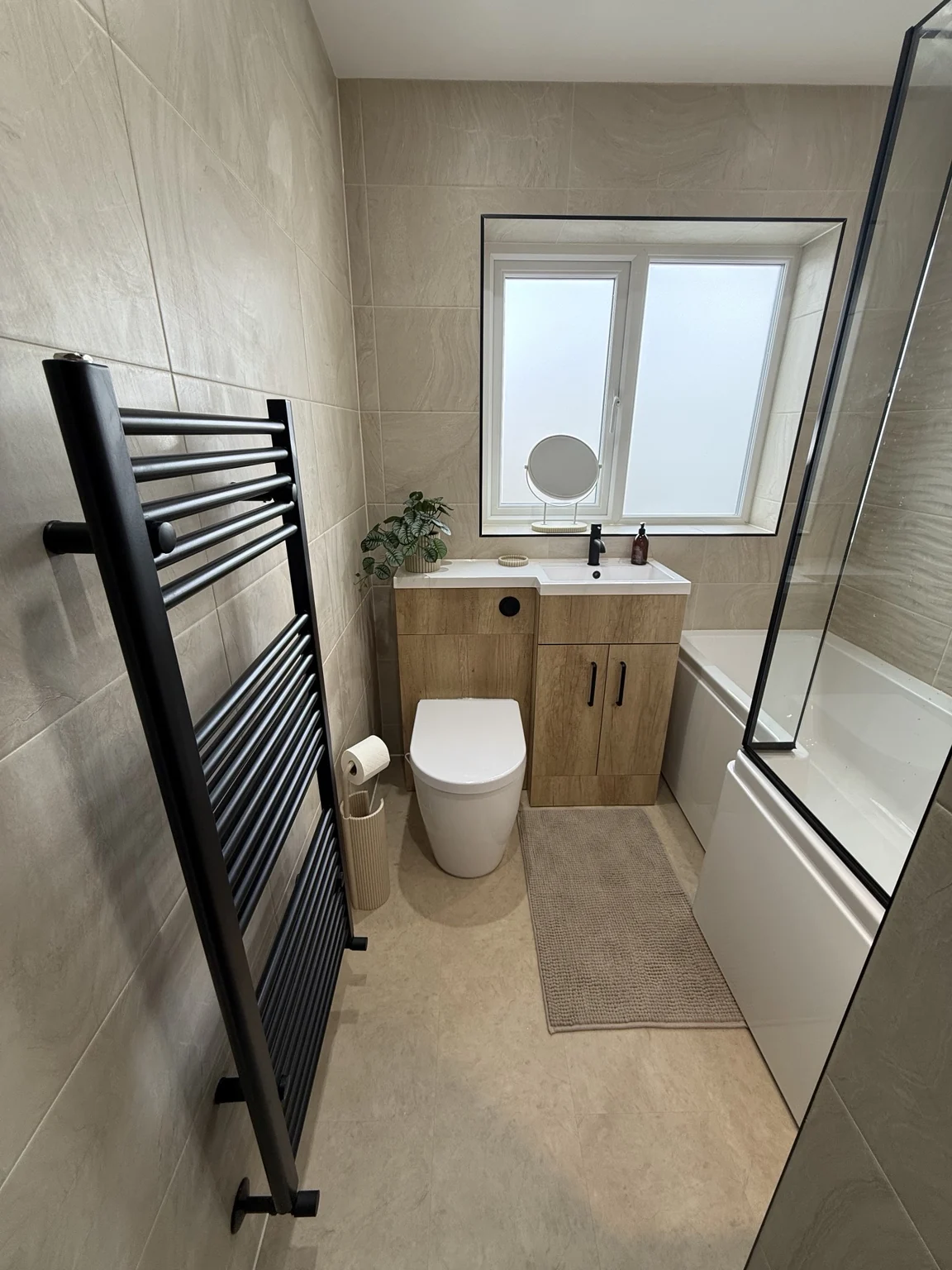 Oak fitted vanity and toilet beside bath with black screen — completed DDI bathroom